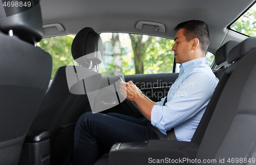 Image of passenger or businessman using smartphone in car