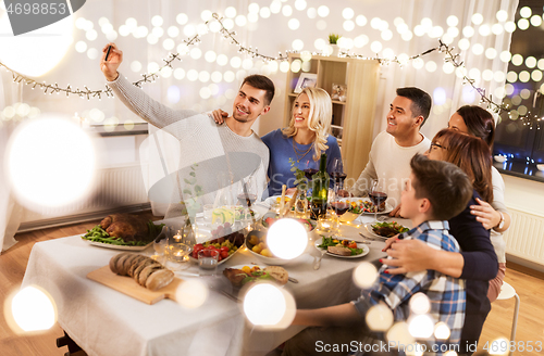 Image of family having dinner party and taking selfie