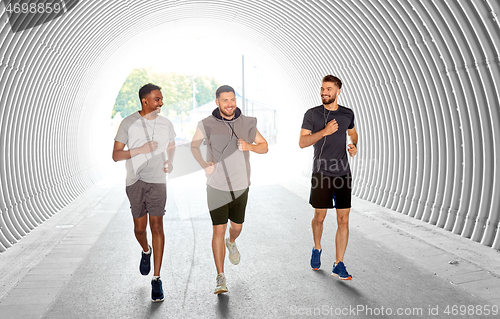 Image of male friends with earphones running outdoors