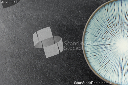 Image of close up of blue ceramic plate on slate background