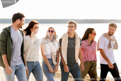 Image of happy friends walking along summer beach