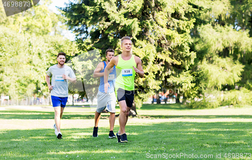 Image of happy young sportsmen racing wit badge numbers