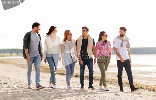 Image of happy friends walking along summer beach