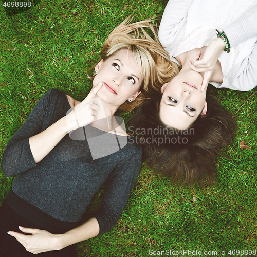 Image of Two thoughtful girls lying in the grass