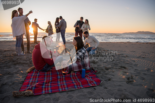 Image of Couple enjoying with friends at sunset on the beach