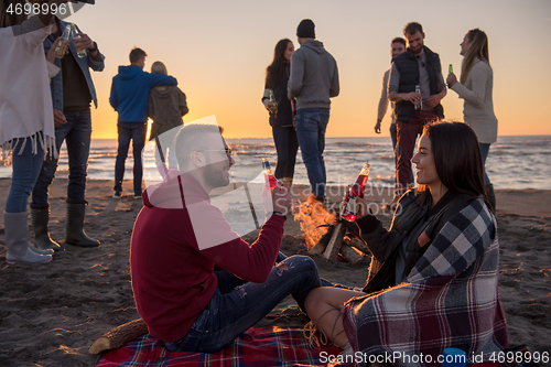 Image of Couple enjoying with friends at sunset on the beach