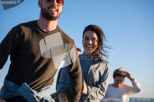 Image of Group of friends running on beach during autumn day