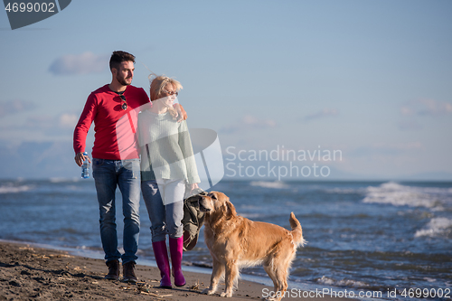 Image of couple with dog having fun on beach on autmun day