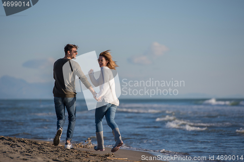 Image of Loving young couple on a beach at autumn sunny day