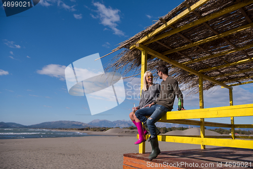 Image of young couple drinking beer together at the beach