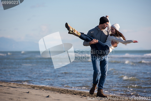 Image of Loving young couple on a beach at autumn sunny day