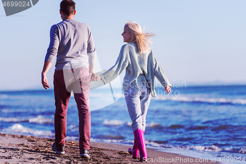 Image of Loving young couple on a beach at autumn sunny day