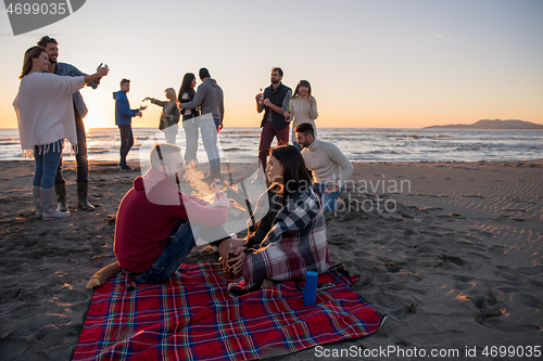 Image of Couple enjoying with friends at sunset on the beach