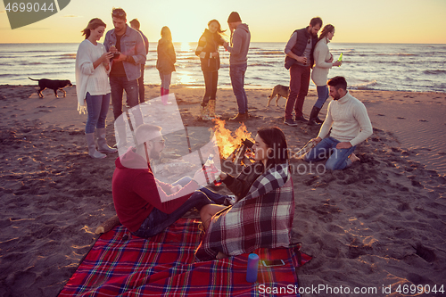 Image of Couple enjoying with friends at sunset on the beach