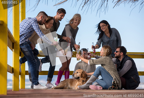 Image of Group of friends having fun on autumn day at beach