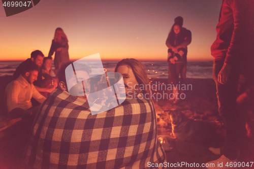 Image of Couple enjoying with friends at sunset on the beach