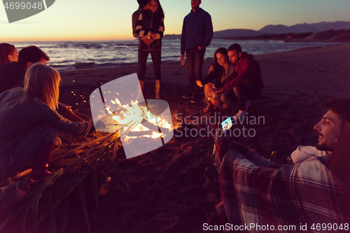 Image of Friends having fun at beach on autumn day