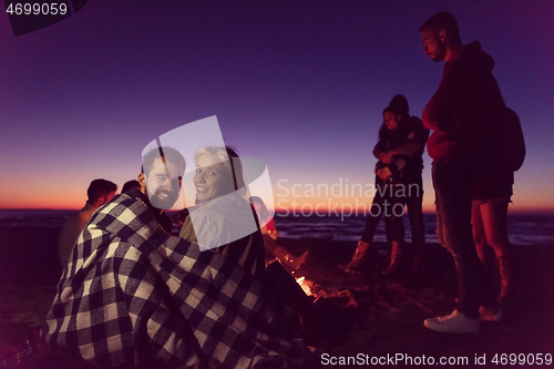 Image of Couple enjoying with friends at sunset on the beach