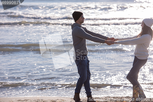 Image of Loving young couple on a beach at autumn sunny day