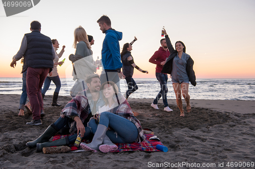 Image of Couple enjoying with friends at sunset on the beach