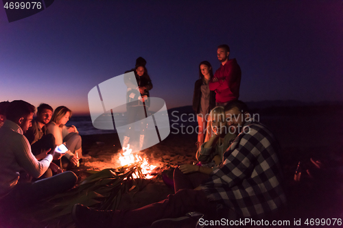 Image of Couple enjoying with friends at sunset on the beach