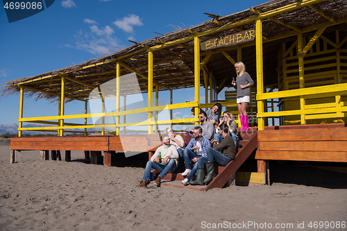 Image of Group of friends having fun on autumn day at beach