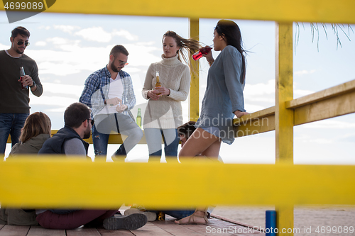 Image of Group of friends having fun on autumn day at beach