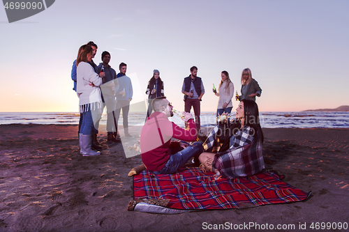 Image of Couple enjoying with friends at sunset on the beach