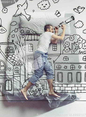 Image of Top view photo of young man sleeping in a big white bed and his dreams