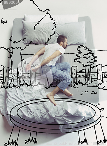 Image of Top view photo of young man sleeping in a big white bed and his dreams