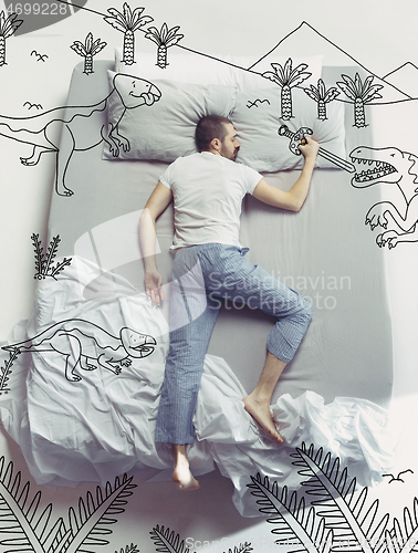 Image of Top view photo of young man sleeping in a big white bed and his dreams