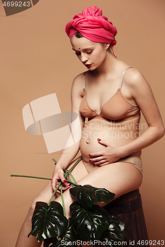 Image of Young beautiful pregnant woman posing on brown background