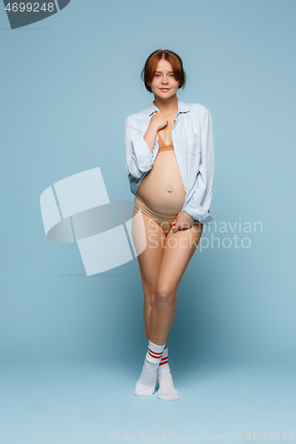 Image of Young beautiful pregnant woman posing on blue background