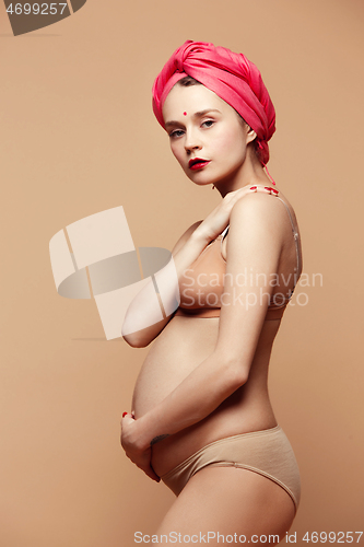 Image of Young beautiful pregnant woman posing on brown background