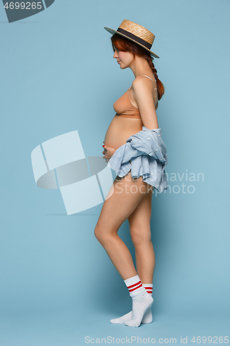 Image of Young beautiful pregnant woman posing on blue background