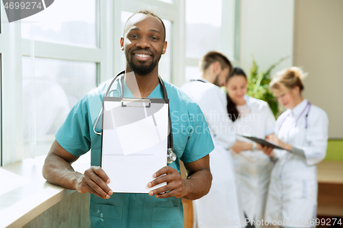 Image of Beautiful smiling african doctor over hospital background