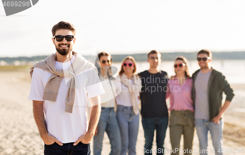 Image of happy man with friends on beach in summer