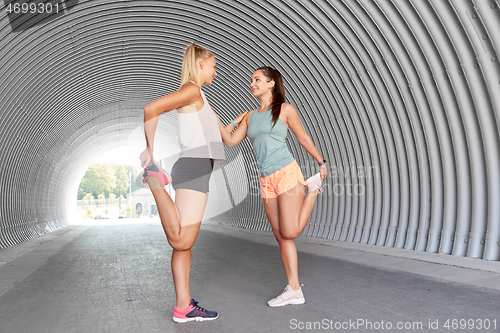 Image of women with fitness trackers stretching outdoors