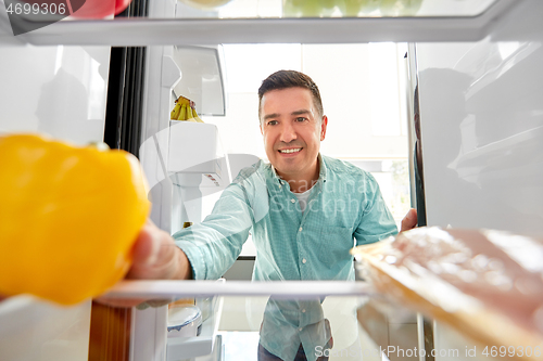 Image of man taking vegetable from fridge at home kitchen