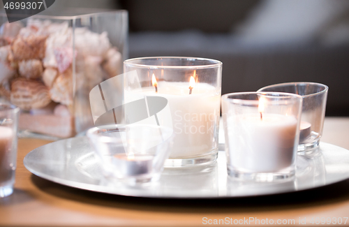 Image of burning white fragrance candles on tray on table