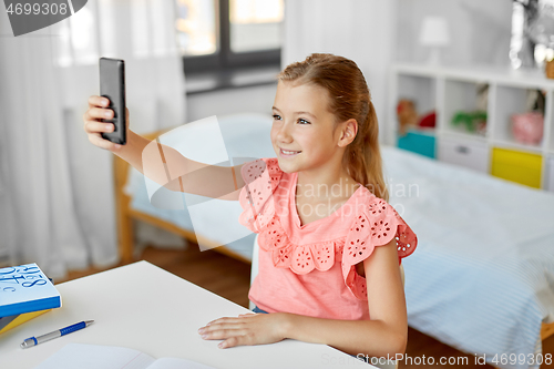 Image of happy girl with smartphone taking selfie at home