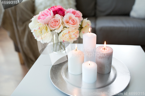 Image of candles burning on table and flowers at cozy home