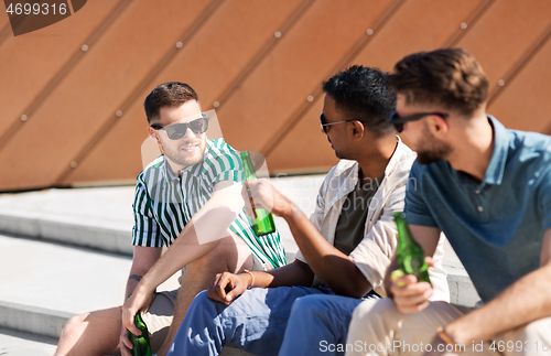 Image of happy male friends drinking beer on street