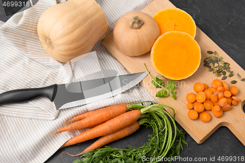 Image of cut pumpkin, carrots and kitchen knife on table