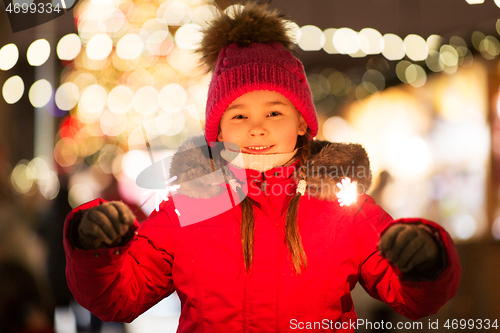Image of happy girl with sparklers at christmas market