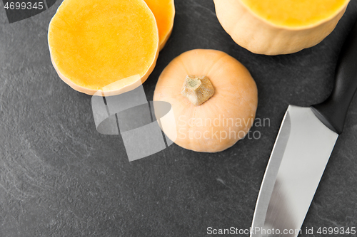 Image of cut pumpkin and kitchen knife on stone background