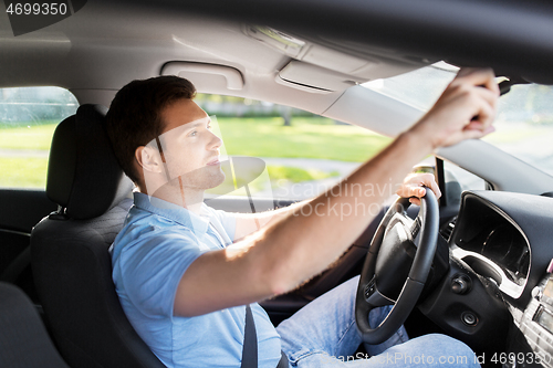 Image of man or car driver adjusting mirror