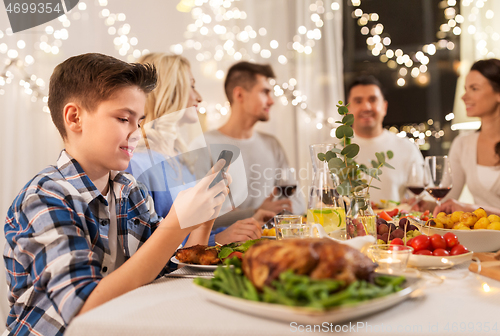 Image of boy with smartphone at family dinner party