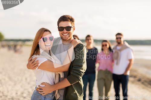 Image of happy friends walking along summer beach