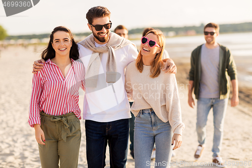 Image of happy friends walking along summer beach